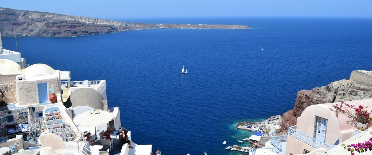 A twilight view of the whitewashed, cave-like buildings and domed churches of Oia village on the island of Santorini, Greece, overlooking the Aegean Sea.