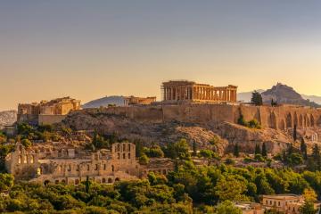 A view of the Acropolis of Athens, featuring the Parthenon and other ruins on the rock, with the Lycabettus hill visible in the background.
