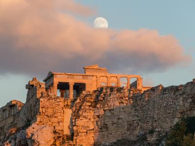 The Erechtheion on the Acropolis of Athens glowing at golden hour beneath a full moon