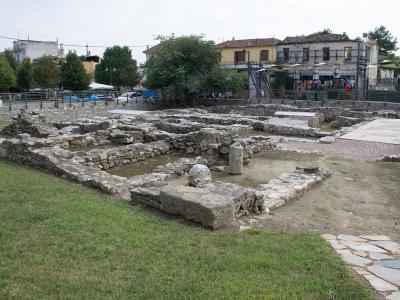 The image shows a close-up of a stone sarcophagus or tomb structure within an archaeological excavation site, partially covered by a modern metal protective shelter.