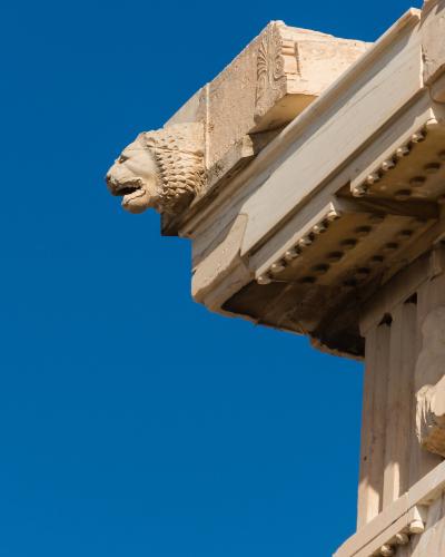 A large ancient Greek marble temple covered in extensive metal scaffolding and a white construction crane, indicating active restoration work.