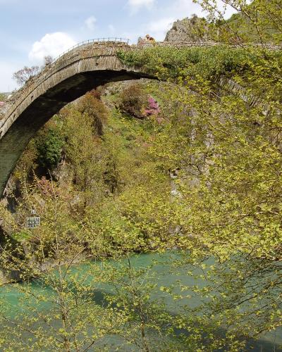 The single high stone arch of the Konitsa bridge over the green Aoos river