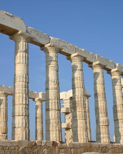 The image shows the ancient Greek temple of Poseidon at Cape Sounion, featuring its iconic Doric columns against a clear blue sky.