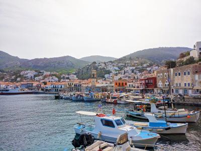 Hydra harbour with fishing boats and stone mansions rising up the hillside