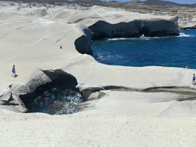 White volcanic rock formations around a turquoise inlet at Sarakiniko, Milos