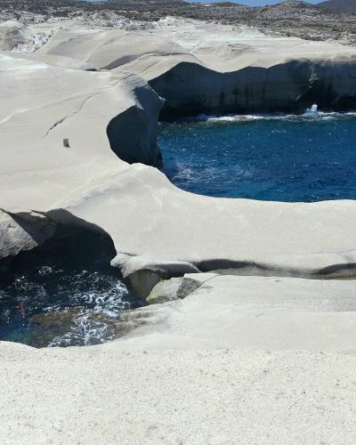 White volcanic rock formations around a turquoise inlet at Sarakiniko, Milos