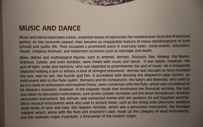 A close-up photograph of an informational museum placard with the heading "MUSIC AND DANCE" and text describing ancient Greek musical instruments and mythology.