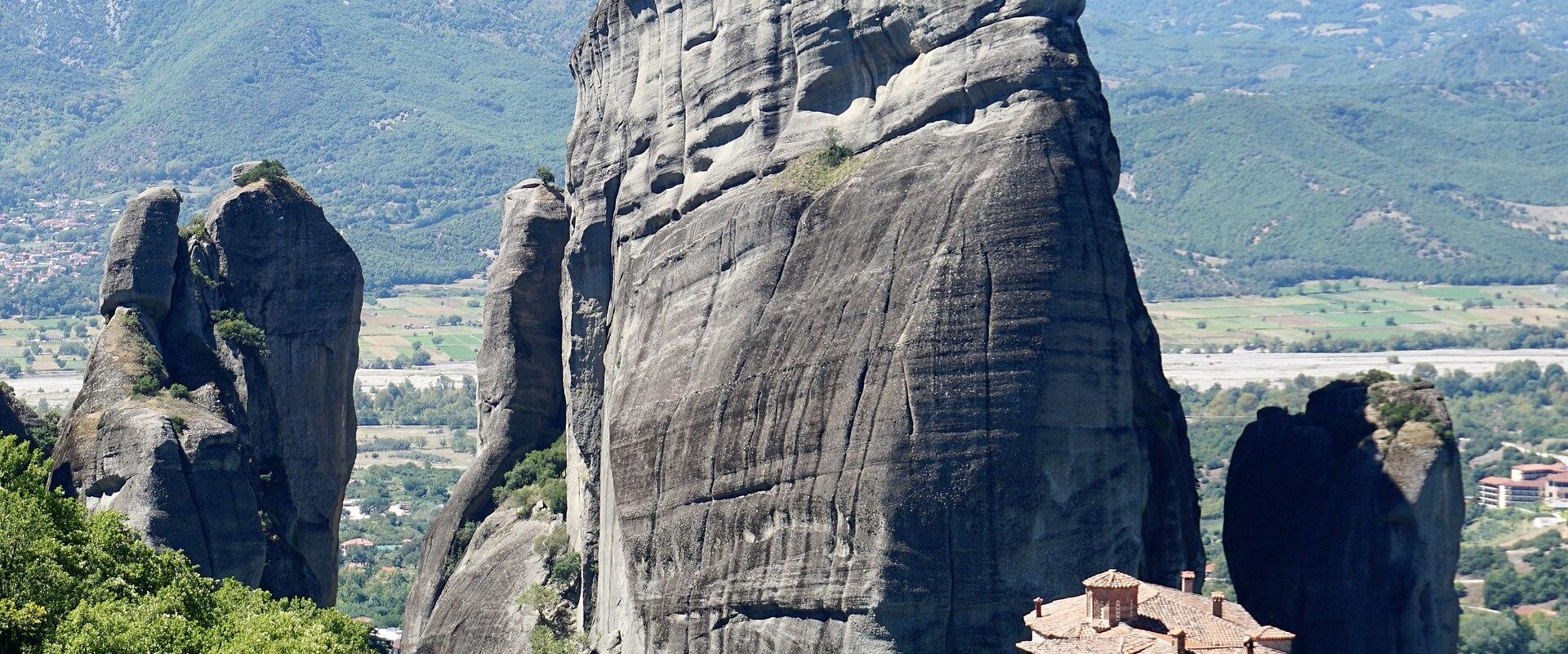 A towering Meteora rock pillar above the Roussanou Monastery, with the Pindus mountains behind