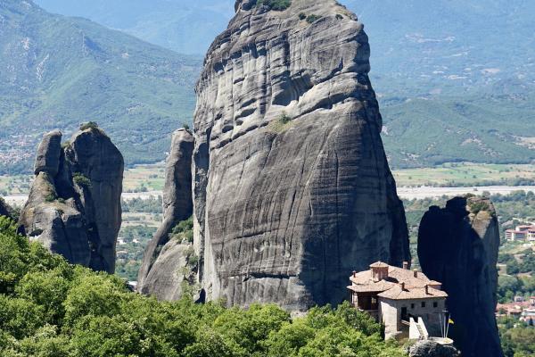 A towering Meteora rock pillar above the Roussanou Monastery, with the Pindus mountains behind
