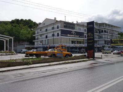 A street-level view of a multi-story white building with a large black sign reading "Fuf reality" and "ALESSANDRO BOSSO" on the facade, alongside a tow truck in the foreground.