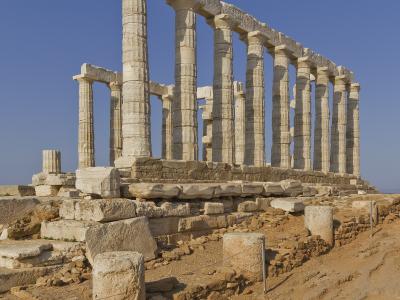 The image shows the ruins of the Temple of Poseidon at Cape Sounion, featuring its iconic Doric columns against a clear blue sky.