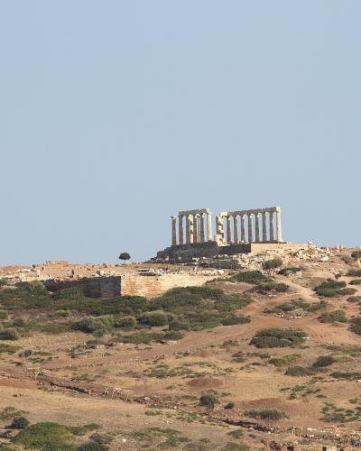 A view of the Temple of Poseidon standing on a rocky coastal promontory with the sea visible in the background.